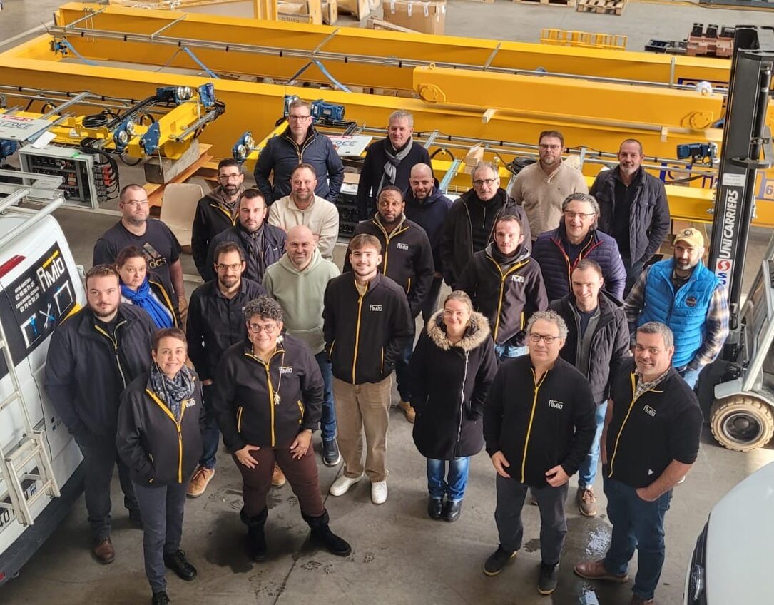 Équipe d’atelier posant devant des équipements industriels.